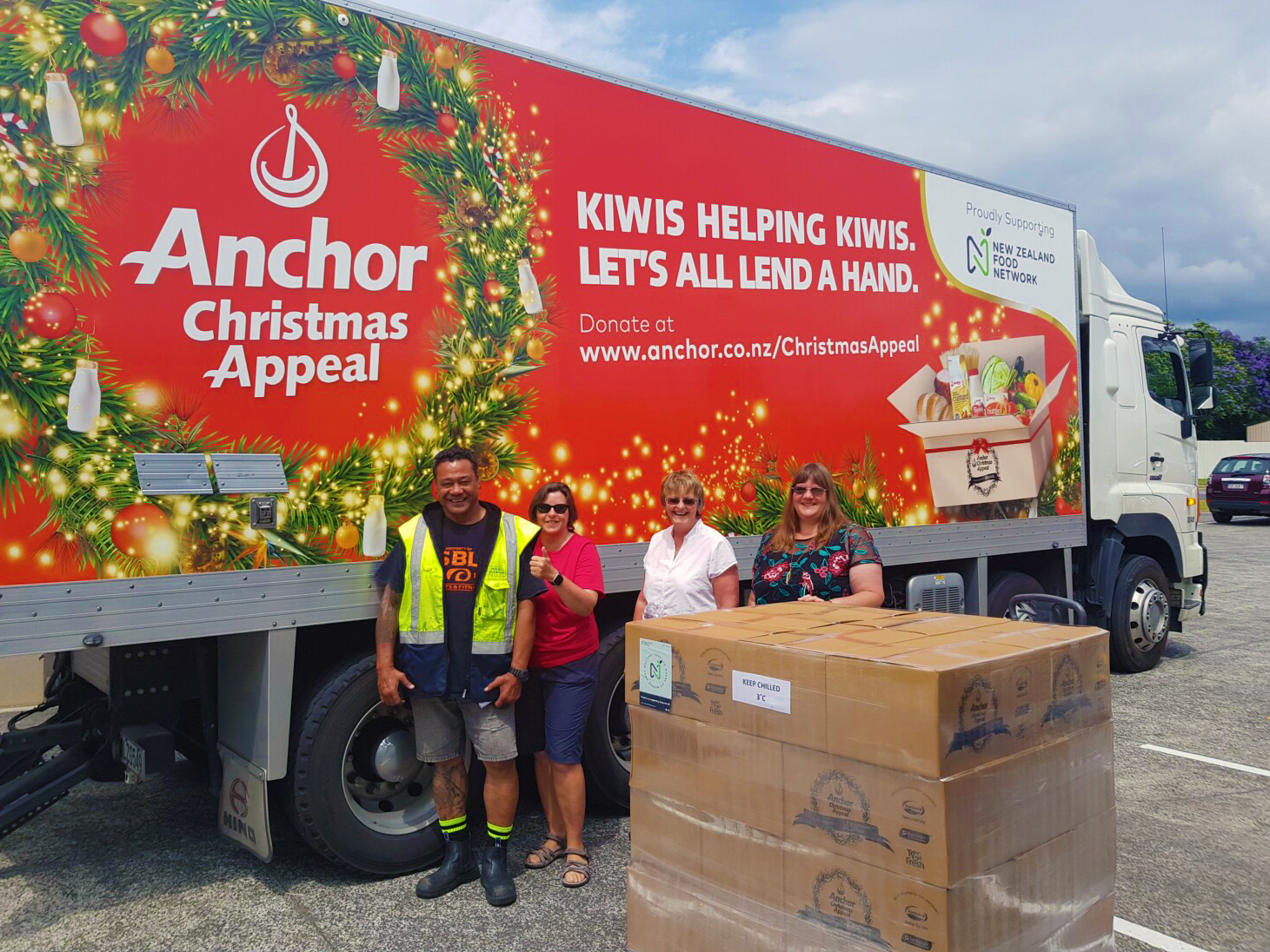 Photo of NZFN Food Hub team and delivery driver standing in front of a Christmas themed Anchor NZ truck with a pallet of donated product.