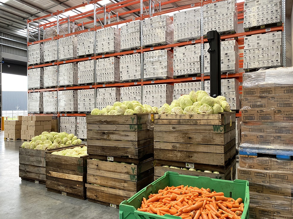 nzfn-home04-min Shot of NZFN warehouse with donated produce bins in the staging area and donated pallets filling the racking.