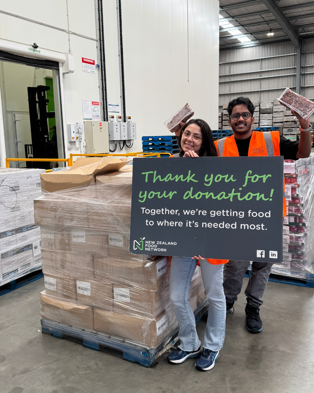 NZFN team members standing in front of a pallet of donated food, holding a sign saying Thank you for your donation