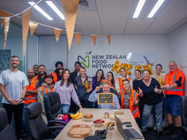 NZFN staff celebrating Best Places to Work Gold certification in office with certificate, decorations and team gathered.